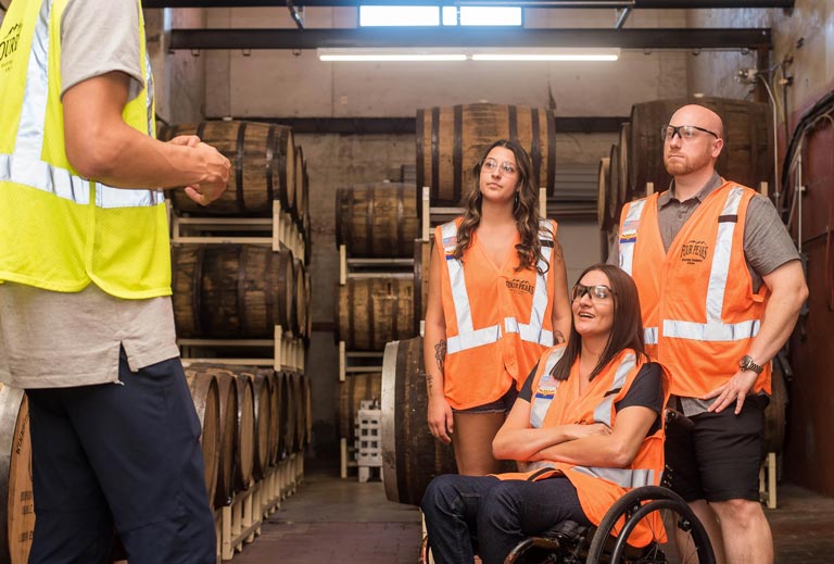 Two women, one in a wheelchair, and a man visiting a warehouse