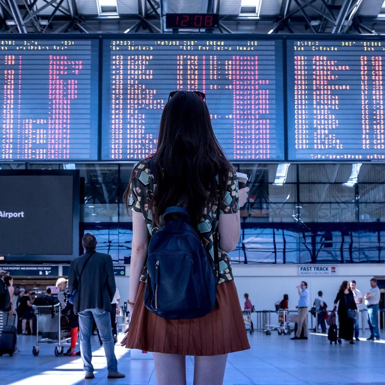 Jeune femme devant des écrans d'affichage dans un aéroport